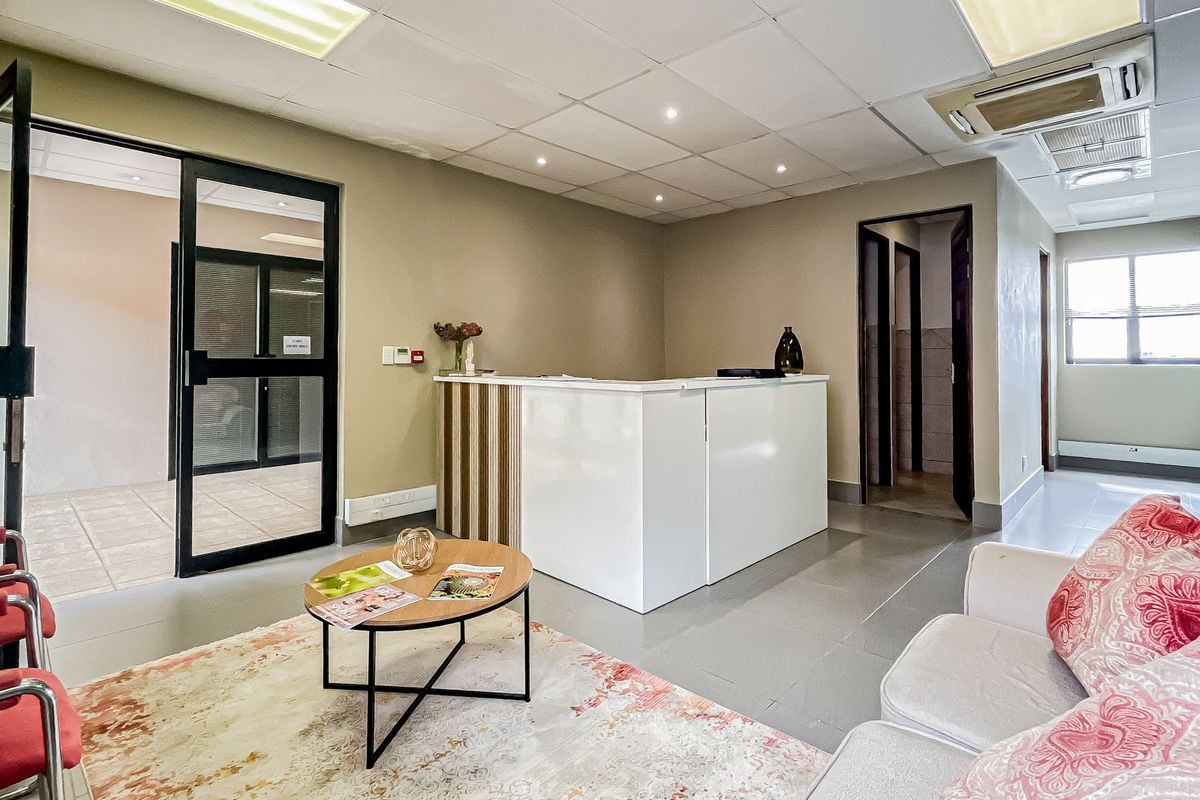 A professional office reception area featuring a built-in reception desk, tiled flooring, suspended ceiling with integrated lighting, and ducted air conditioning.