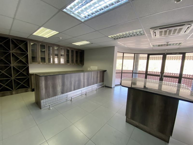 Spacious industrial bar area featuring built-in cabinetry, wine storage, a central island, tiled flooring, and recessed ceiling lighting with integrated air conditioning.