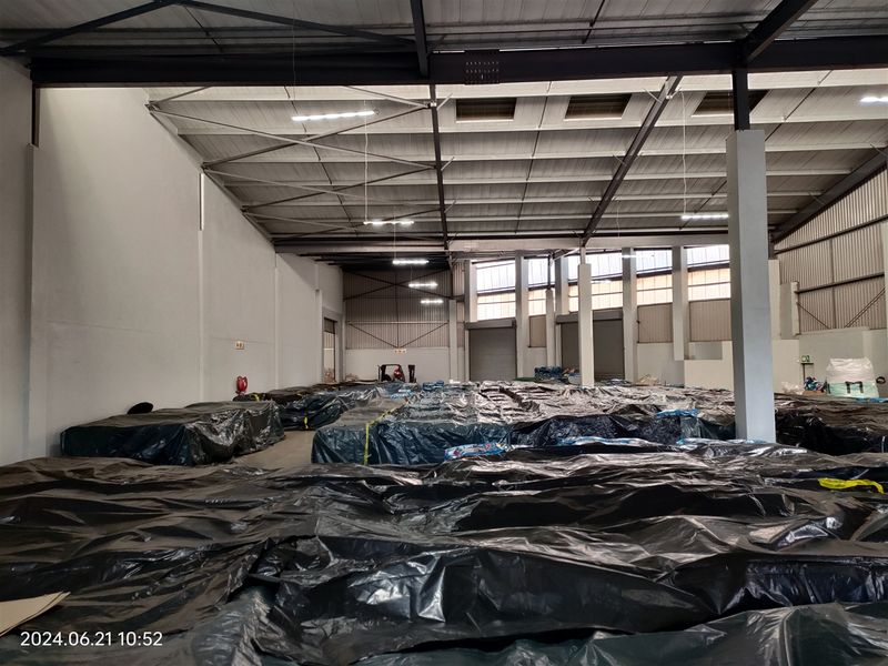 Spacious industrial warehouse featuring a high-clearance steel portal frame, concrete flooring, and multiple roller shutter doors for efficient logistics and storage operations.