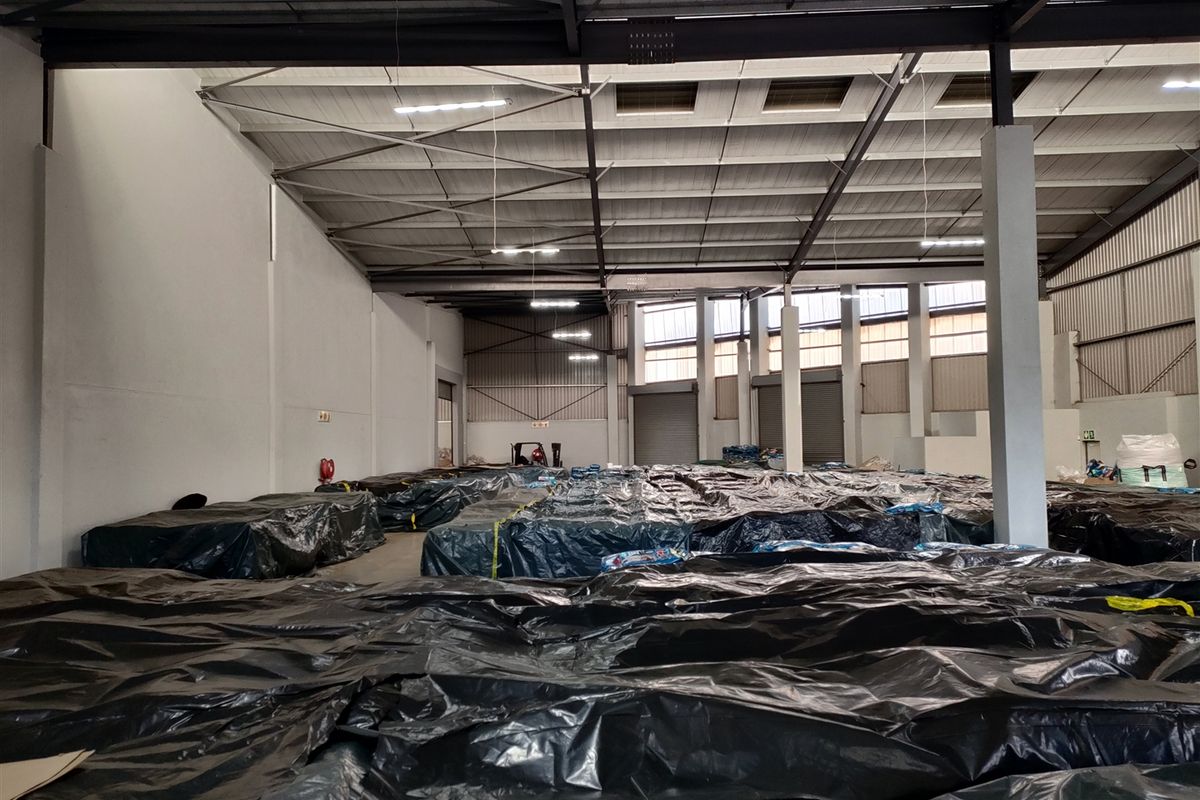 Spacious industrial warehouse featuring a high-clearance steel portal frame, concrete flooring, and multiple roller shutter doors for efficient logistics and storage operations.