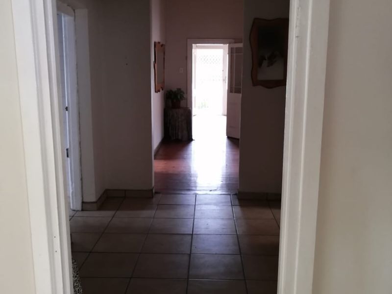 A view through a doorway into a tiled hallway leading towards an exterior exit, featuring neutral walls and an arched transition.