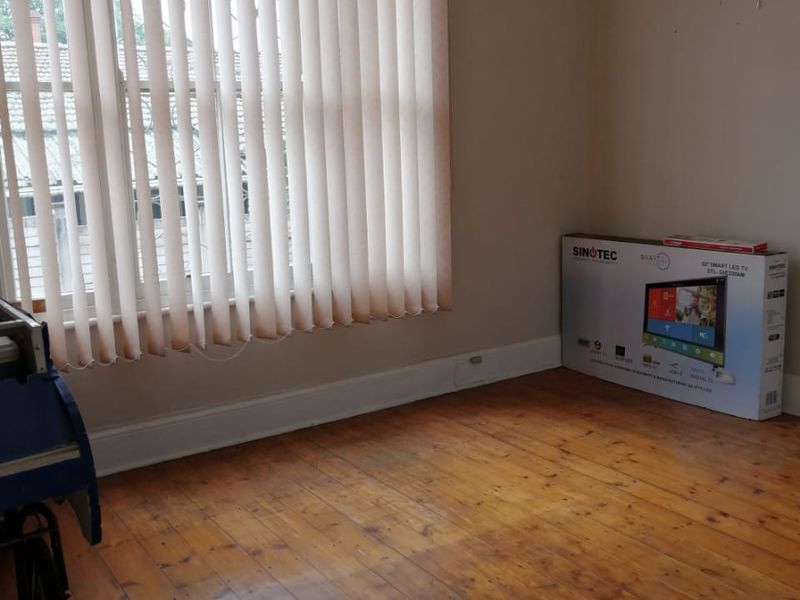 An empty bedroom featuring original timber flooring, vertical window blinds, and neutral wall finishes, offering a blank canvas for renovation or staging.
