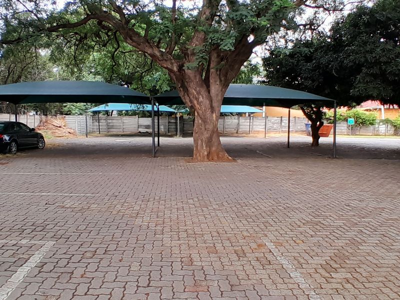 Outdoor paved parking area featuring multiple shade cloth carports and secure precast concrete boundary walling.