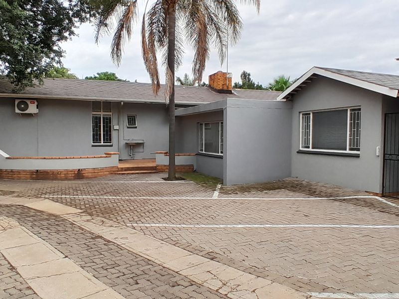 Front exterior view of the business premises featuring a paved parking area, brick retaining wall, and secure building access points.
