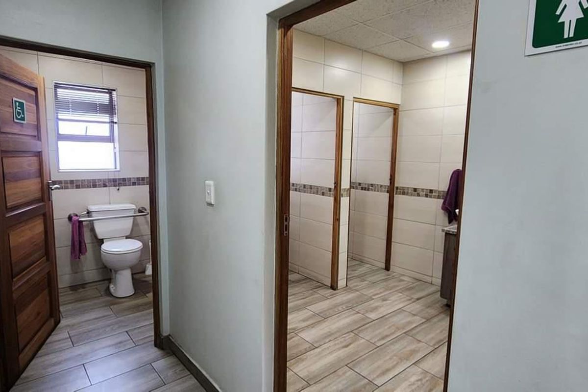 A commercial restroom facility featuring tiled flooring, multiple cubicles, and a separate accessible toilet area with modern finishes.