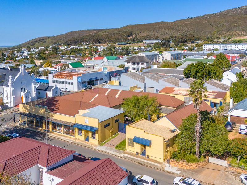 Aerial view of a commercial property complex featuring multiple pitched roof structures and street-level storefronts in a town setting.