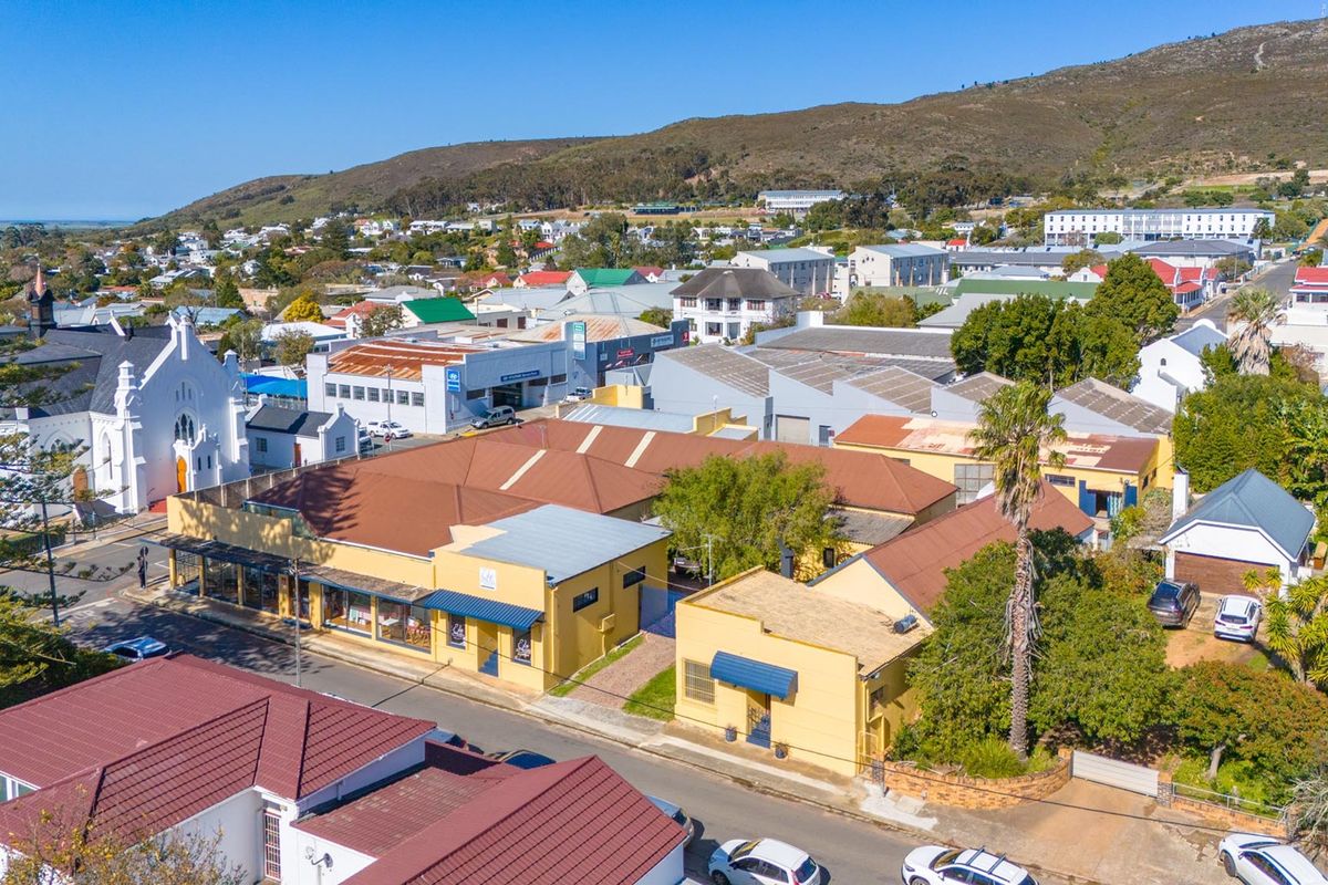 Aerial view of a commercial property complex featuring multiple pitched roof structures and street-level storefronts in a town setting.
