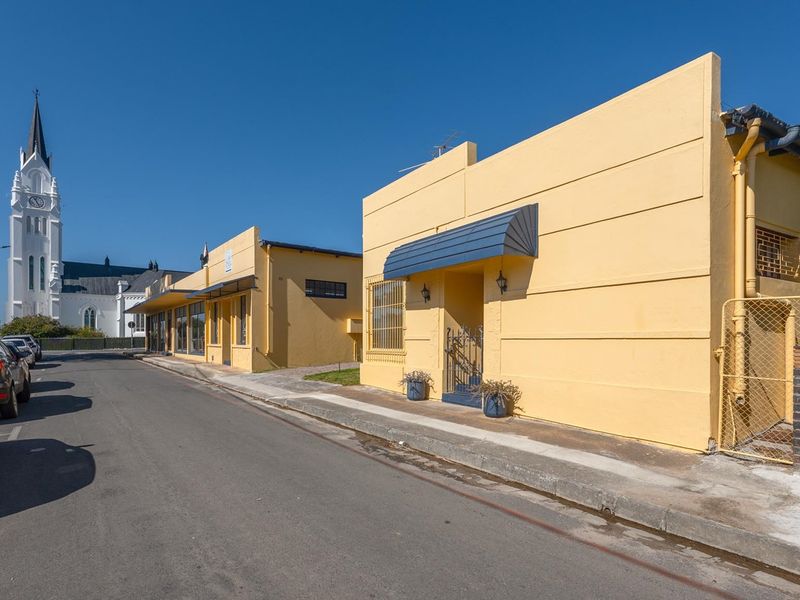 Street view of a commercial property featuring yellow painted facades, awnings, and security fixtures, located in a well-maintained neighborhood.