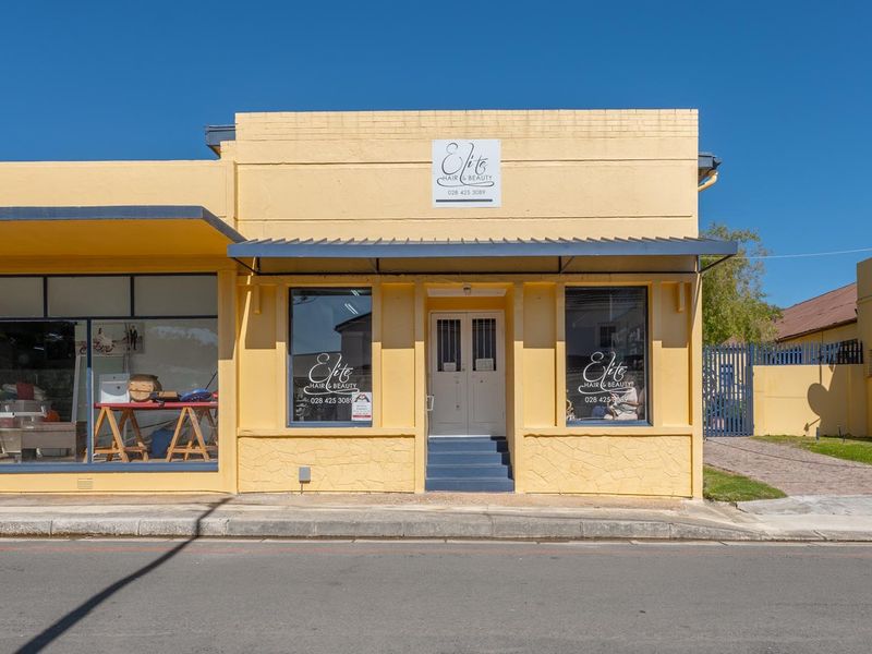 Commercial street-front property featuring a prominent yellow brick facade, large display windows, and a metal awning entrance.