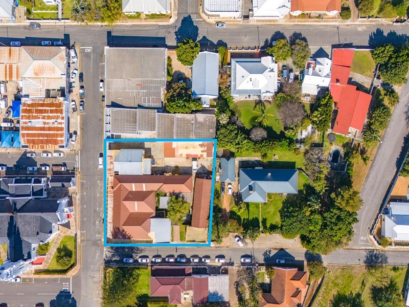 Aerial view of a commercial property featuring multiple roof sections, a central courtyard, and surrounding street access in a town setting.