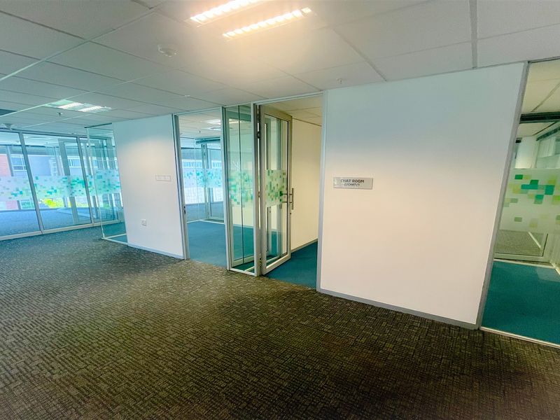 Modern office space featuring glass partition walls, carpeted flooring, and recessed lighting, providing a clean and professional environment for business operations.