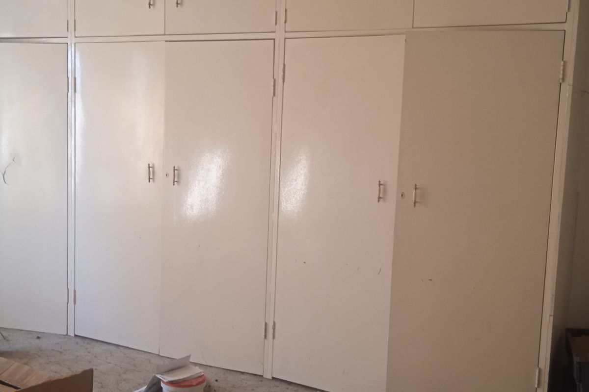 A bedroom featuring extensive built-in cupboards with overhead storage, providing ample storage space. The room is currently vacant and ready for updates.