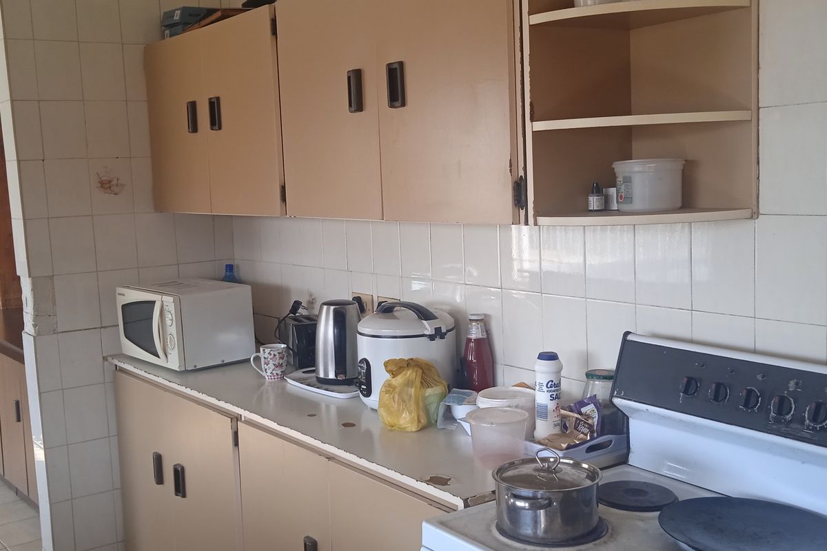 A dated kitchen featuring original built-in cabinetry, tiled backsplash, and a freestanding electric stove, offering potential for a modern renovation.