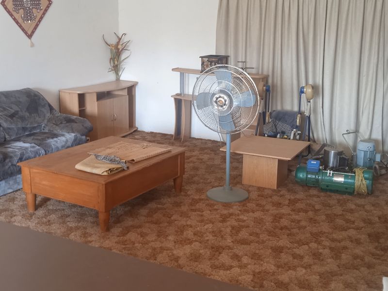A living room area featuring dated wall-to-wall carpeting and neutral curtains, offering a blank canvas for potential modernization and interior updates.