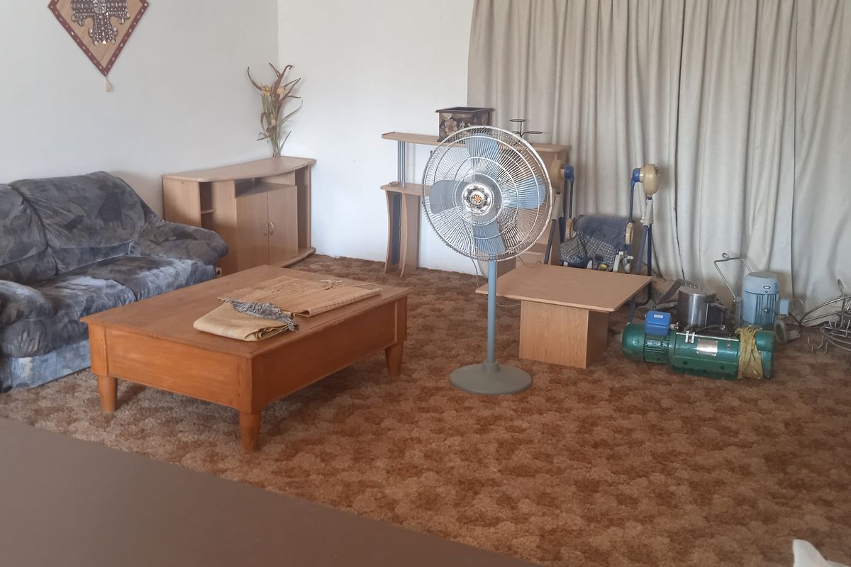 A living room area featuring dated wall-to-wall carpeting and neutral curtains, offering a blank canvas for potential modernization and interior updates.