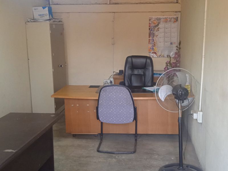 A functional office space featuring plain walls, basic electrical infrastructure, and a built-in metal storage cabinet, suitable for a home workspace or administrative area.