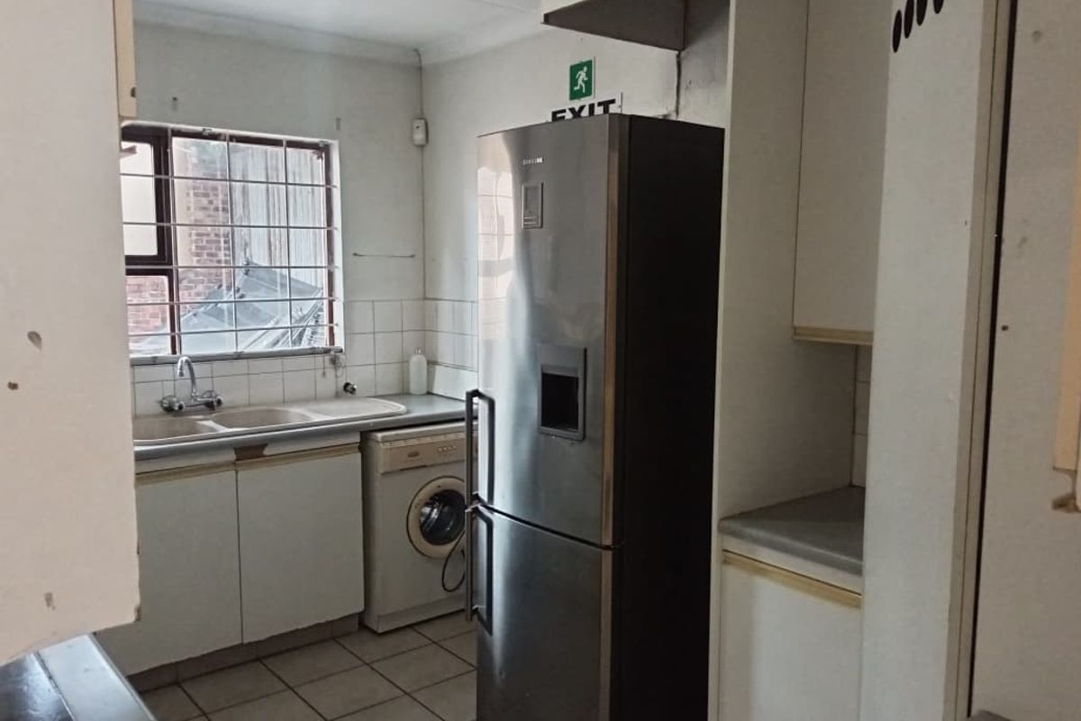 Functional office kitchenette featuring built-in cabinetry, double basin sink, tiled flooring, and space for integrated appliances.
