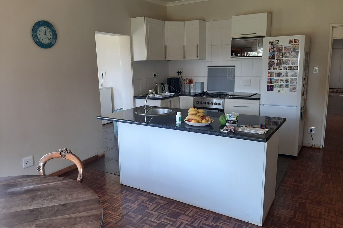 A functional kitchen featuring a central island with a sink, white cabinetry, and a gas stove, set against a backdrop of parquet flooring.