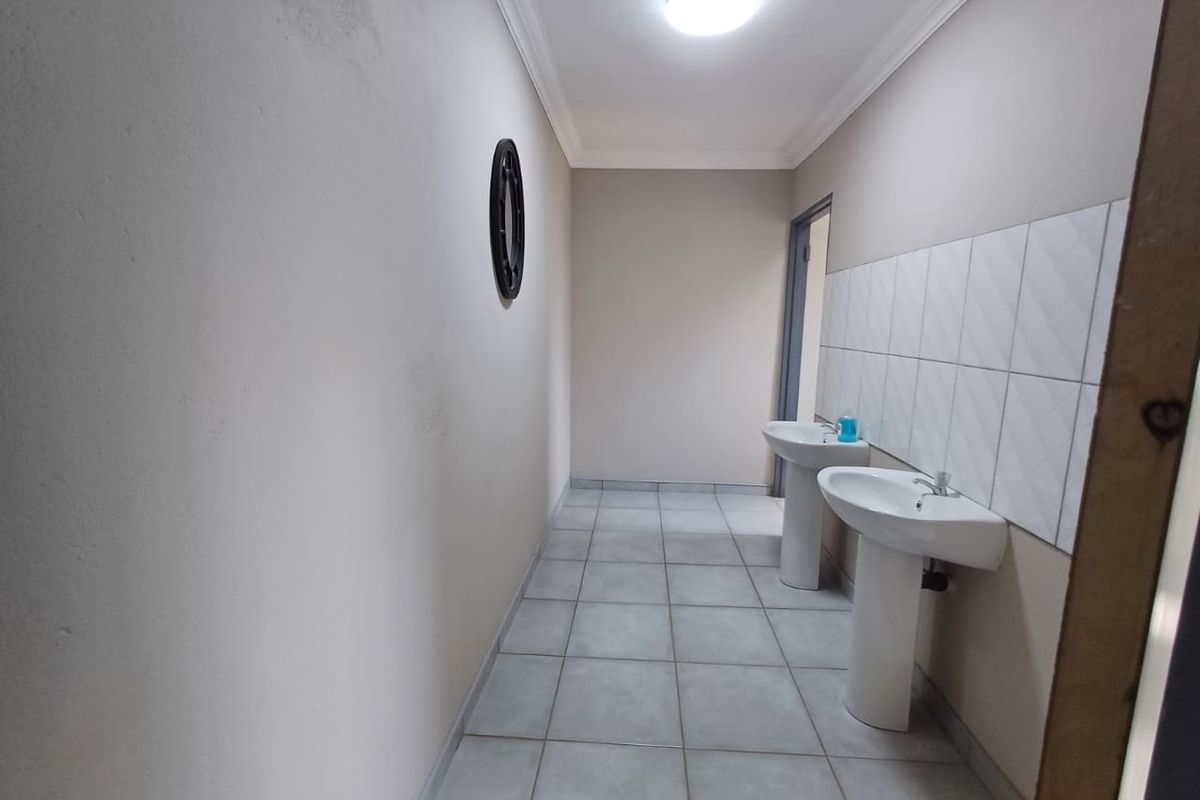 A functional washroom area featuring dual pedestal basins, tiled splashbacks, and neutral floor tiling, suitable for industrial or commercial use.