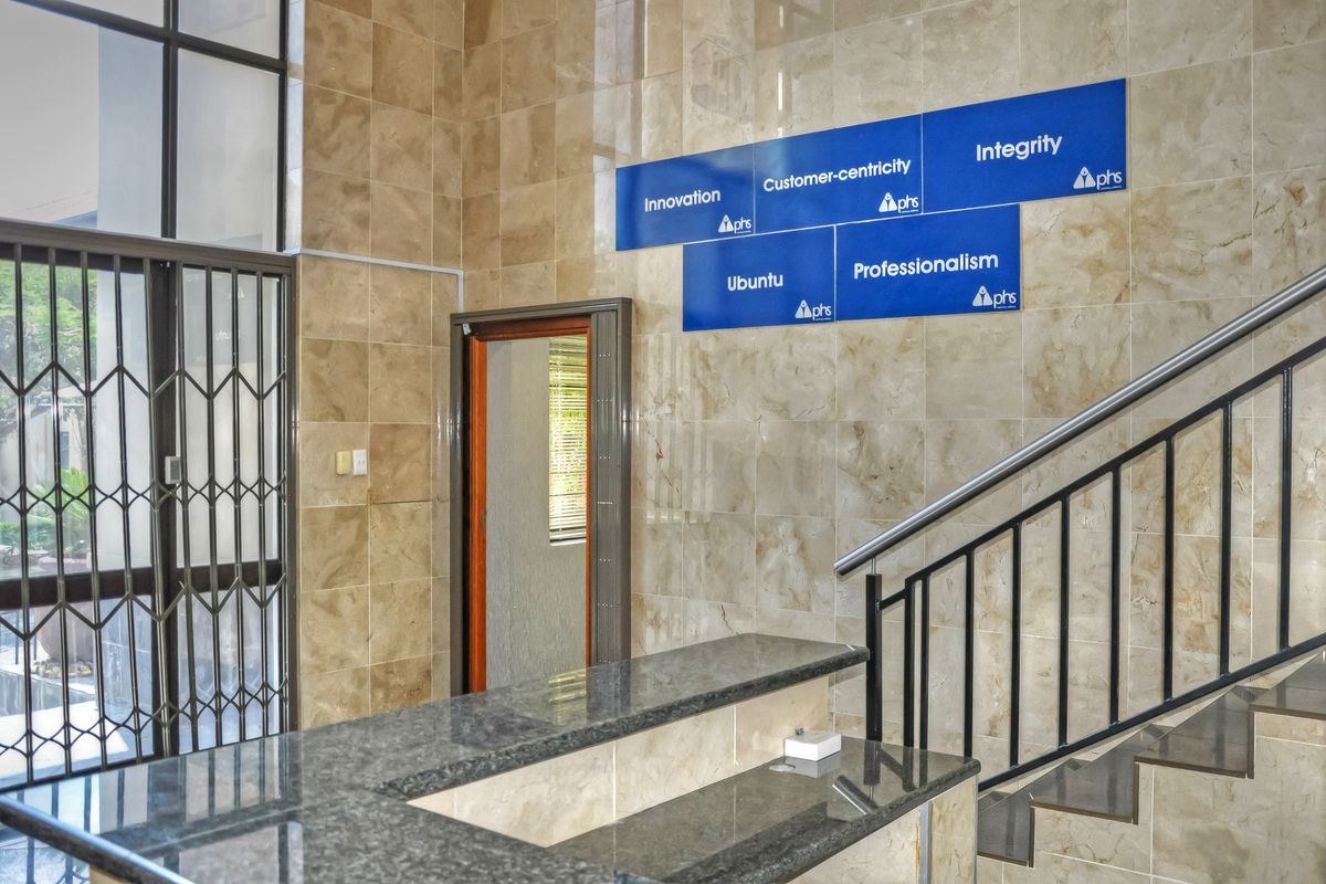 Professional office entry area featuring polished tiled wall cladding, a granite reception counter, and a secure metal staircase.
