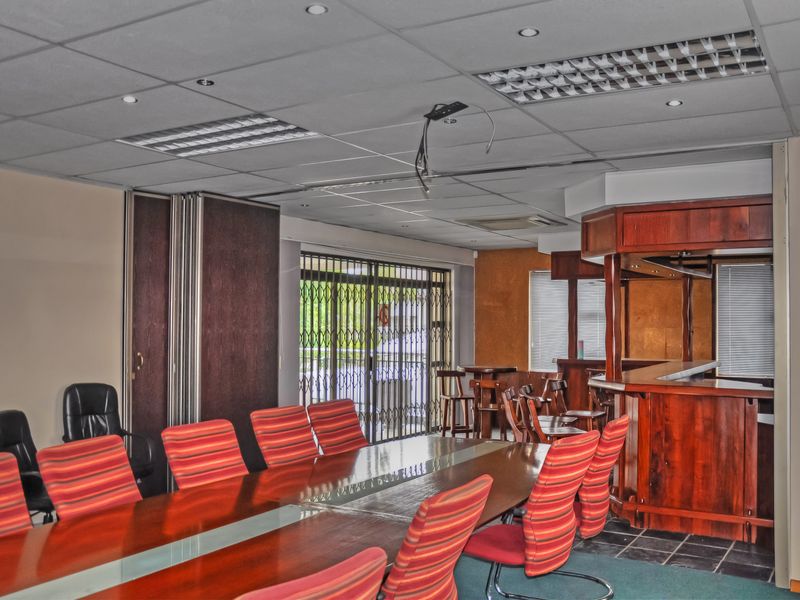 Office space featuring a built-in bar counter, suspended ceiling with recessed lighting, and a folding partition door for flexible room configuration.
