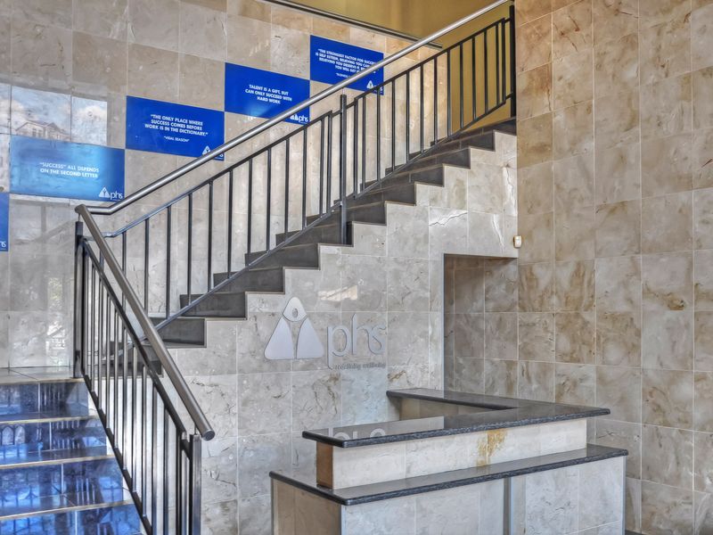 A professional office entrance featuring stone wall cladding, a built-in reception desk, and a central staircase with metal railings.
