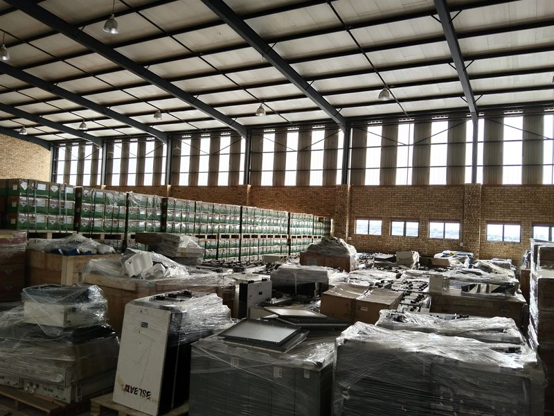 Spacious industrial warehouse featuring high-bay lighting, exposed steel roof trusses, and face brick walls, currently utilized for storage.