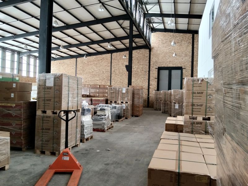 Spacious industrial warehouse featuring high ceilings with exposed steel trusses, brick wall finishes, and durable concrete flooring, currently utilized for storage.