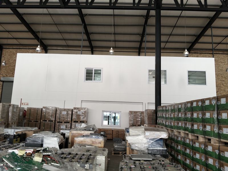 Spacious industrial warehouse featuring high ceilings with exposed steel trusses, a mezzanine level, and functional storage areas with ample natural light.
