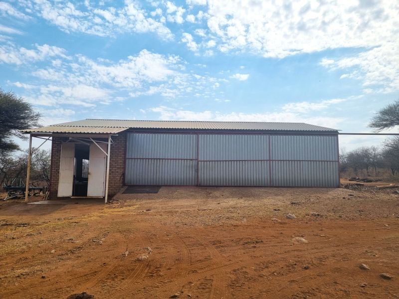 A functional farm outbuilding featuring corrugated metal cladding and a metal roof, situated on a rural property.