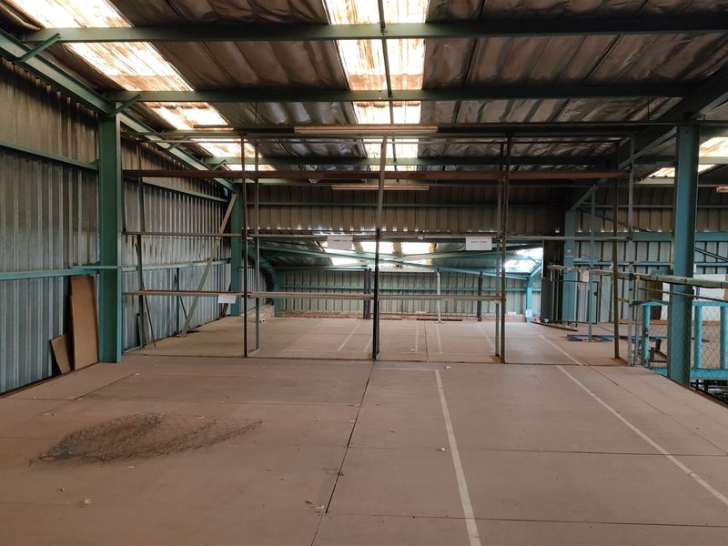 Spacious industrial mezzanine level featuring a steel frame structure, corrugated metal walls, and integrated shelving units, suitable for storage or workshop use.