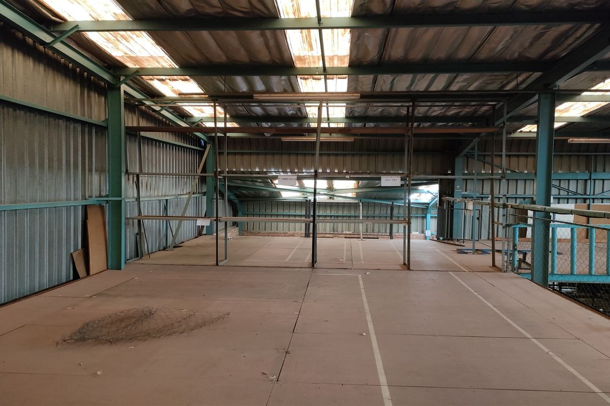 Spacious industrial mezzanine level featuring a steel frame structure, corrugated metal walls, and integrated shelving units, suitable for storage or workshop use.