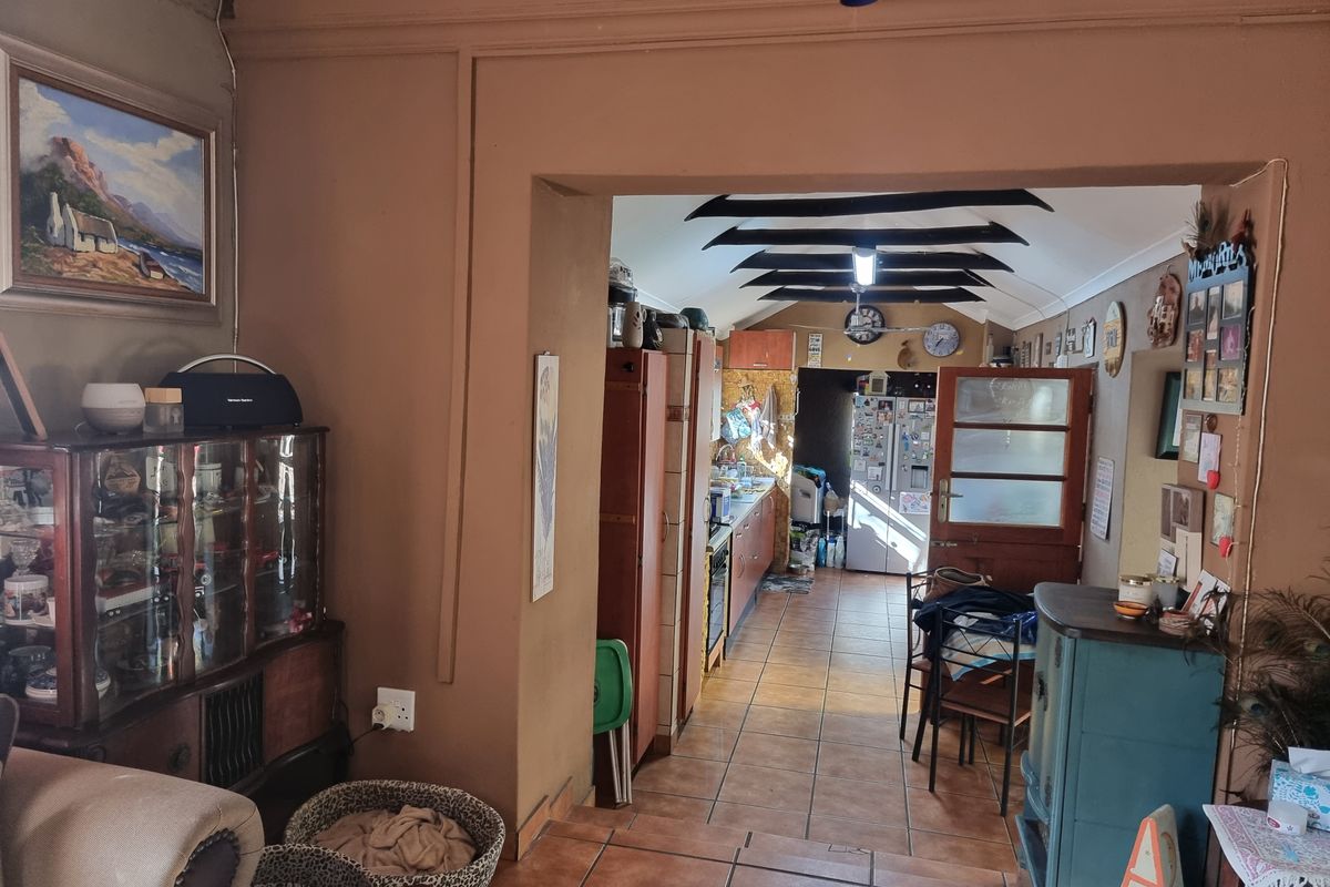 A view from the living area into a galley-style kitchen featuring tiled floors, exposed ceiling beams, and built-in cabinetry with integrated appliances.