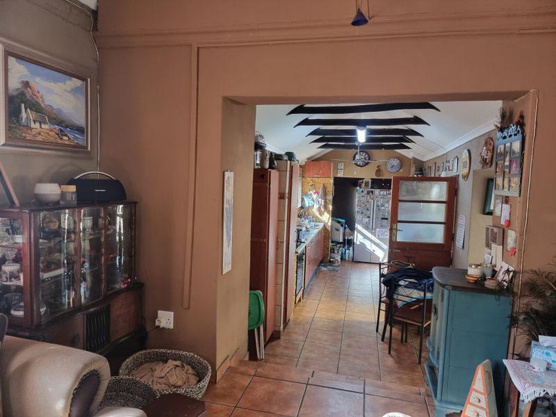 A view from the living area into a galley-style kitchen featuring tiled floors, exposed ceiling beams, and built-in cabinetry with integrated appliances.