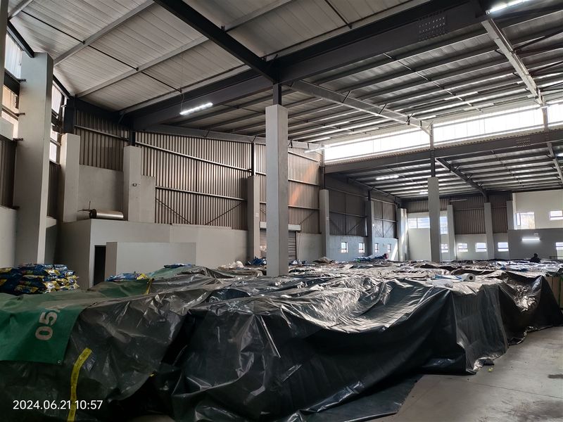 Spacious industrial warehouse featuring a high-clearance steel portal frame, corrugated metal walls, and concrete flooring, suitable for storage or manufacturing operations.