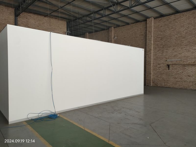 Spacious industrial utility area featuring exposed brick walls, steel roof trusses, and a large partition wall, suitable for various commercial or storage applications.