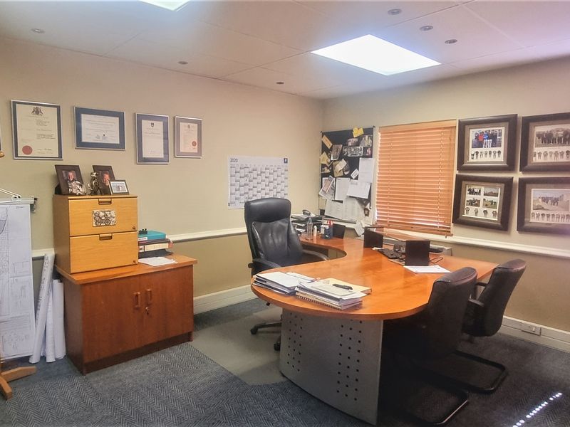A functional office space featuring recessed ceiling lighting, carpeted flooring, and venetian blinds, providing a professional environment suitable for daily business operations.