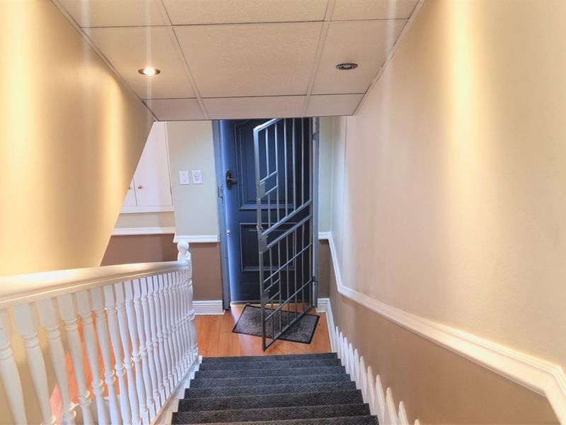 A well-lit interior staircase featuring a wooden balustrade, chair rail molding, and a secure metal gate at the landing.