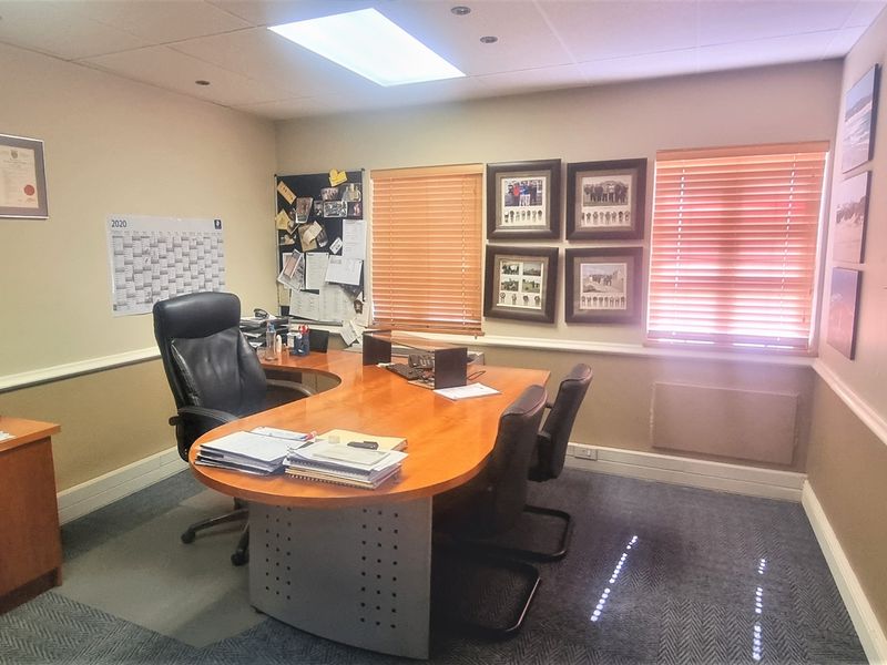 A functional office space featuring carpeted flooring, recessed ceiling lighting, venetian blinds, and a large wall-mounted whiteboard.