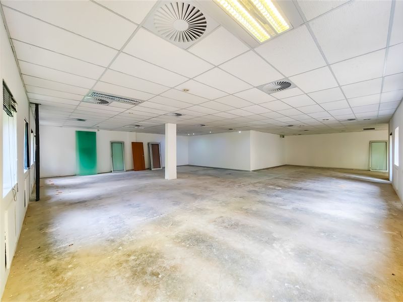A large, open-plan office space featuring a suspended ceiling with integrated lighting and air conditioning, currently in a shell condition.