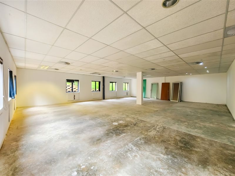A large, open-plan office space featuring a suspended ceiling, recessed lighting, and exposed concrete flooring, offering a blank canvas for custom fit-outs.