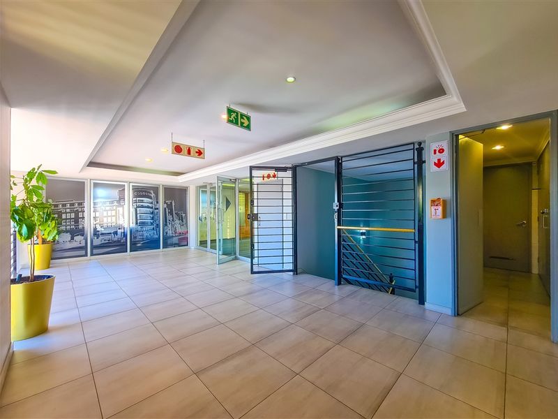 A well-maintained office building hallway featuring tiled flooring, recessed ceiling lighting, and secure access points with integrated fire safety equipment.