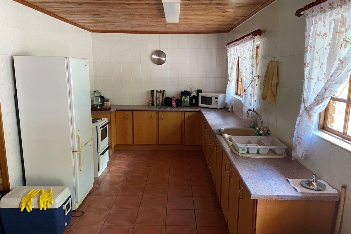 Functional kitchen featuring timber ceiling, tiled splashbacks, laminate cabinetry, and a double basin sink, offering a traditional farm-style aesthetic.
