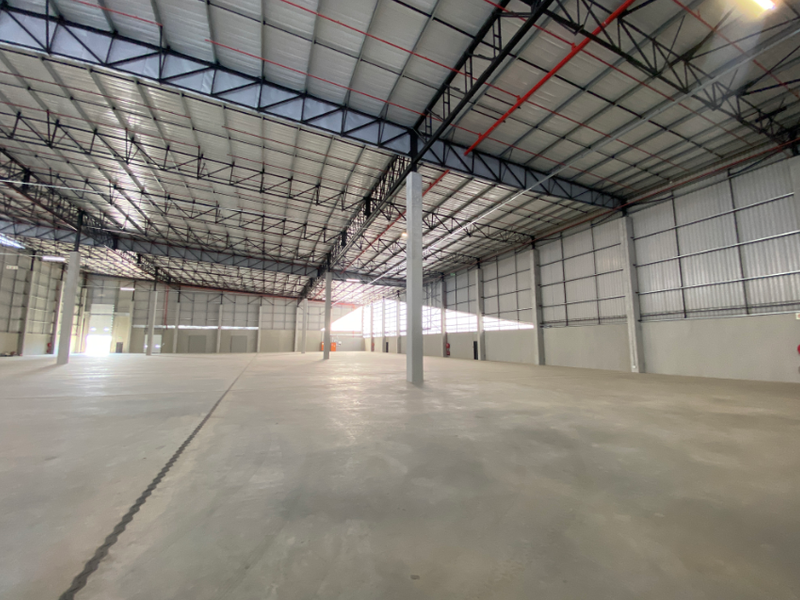 Spacious industrial warehouse featuring high ceilings with exposed steel trusses, polished concrete flooring, and integrated fire sprinkler systems.