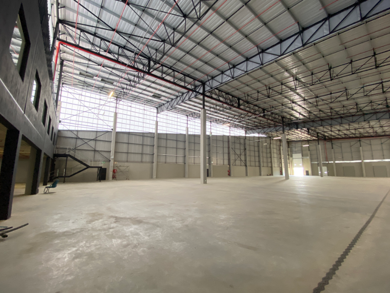 Spacious industrial warehouse featuring high ceilings with exposed steel trusses, polished concrete flooring, and integrated fire safety systems.