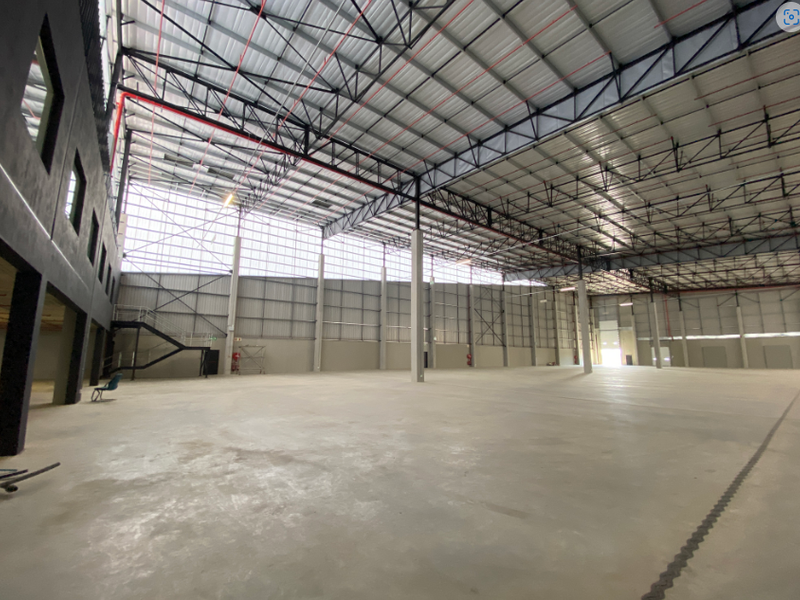 Spacious industrial warehouse featuring high ceilings with exposed steel trusses, polished concrete flooring, and a mezzanine level with integrated staircase access.
