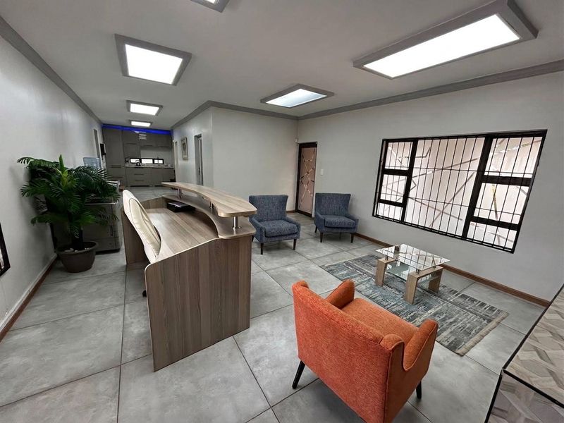 A professional office reception area featuring tiled flooring, recessed LED lighting, and a built-in reception desk with a waiting area.