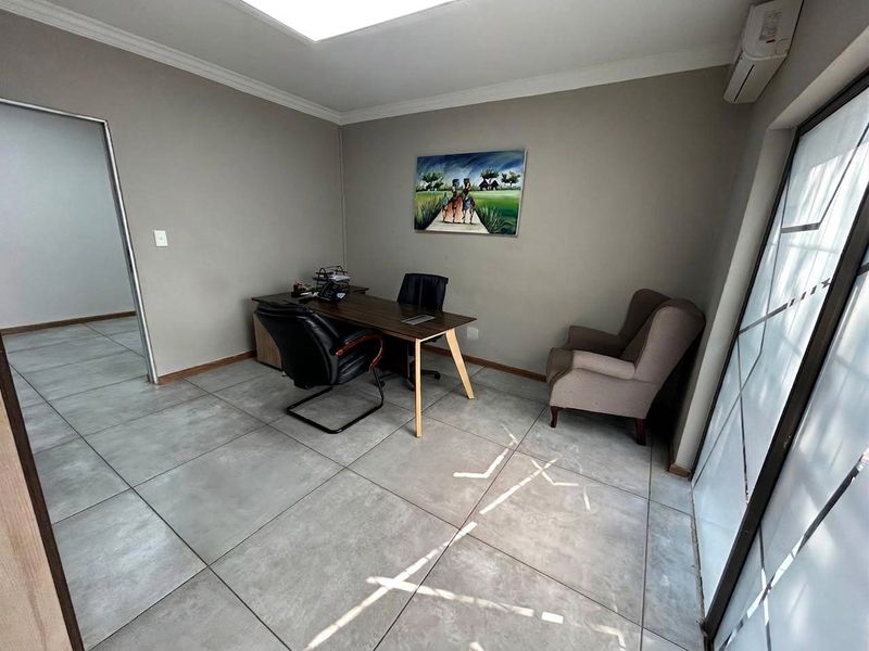 A professional office space featuring large format floor tiles, a modern air conditioning unit, and a sleek frosted glass partition.