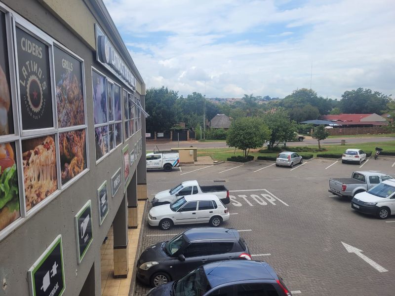 Elevated view of a retail property facade featuring prominent signage and an adjacent paved parking lot with marked bays.