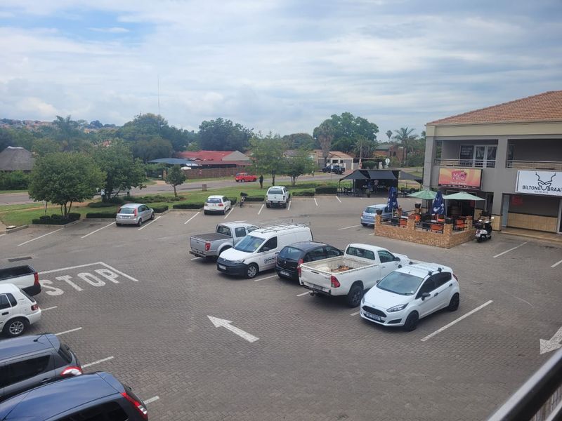 An elevated view of a commercial retail property featuring a paved parking lot and an outdoor seating area adjacent to the building.